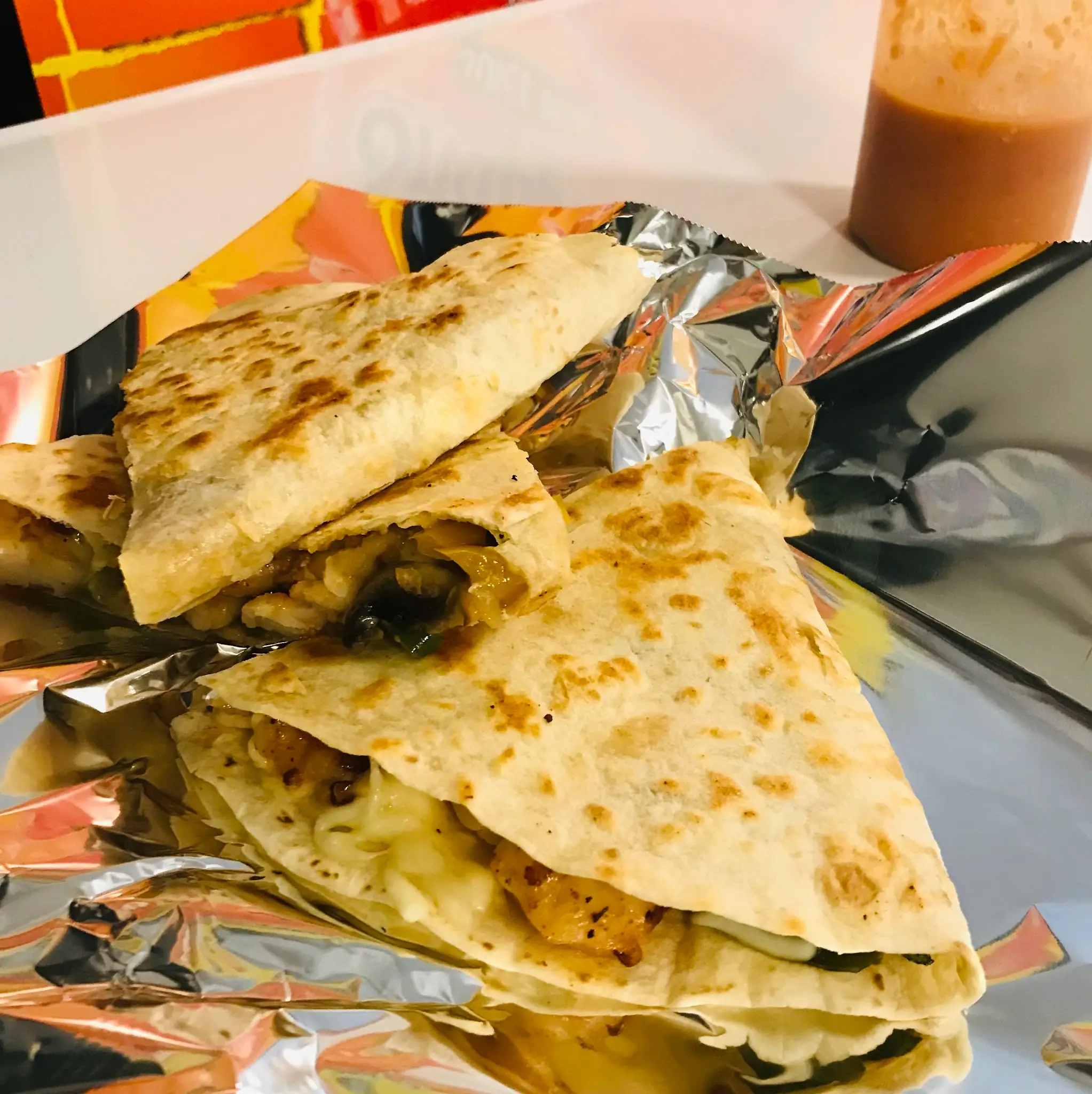 Quesadilla wedges with melted cheese on foil, a bottle of salsa behind